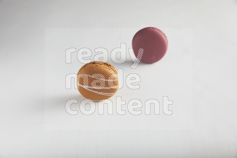 45º Shot of of two assorted Brown Irish Cream, and Red Cherry macarons on white background