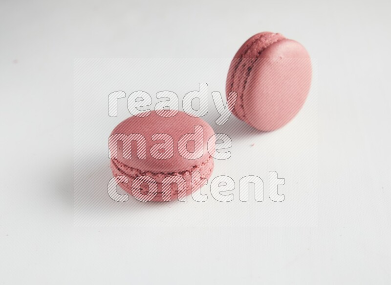 45º Shot of two Pink Raspberry macarons on white background