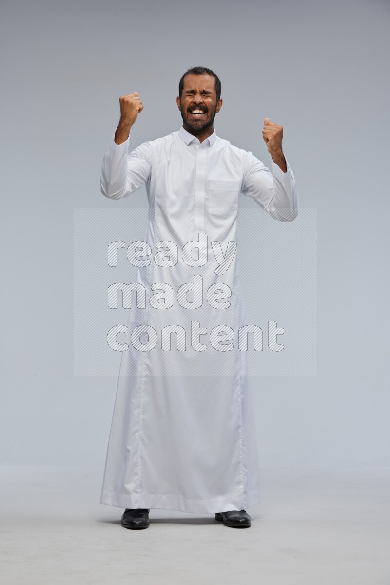 Saudi man Wearing Thob standing interacting with the camera on Gray background