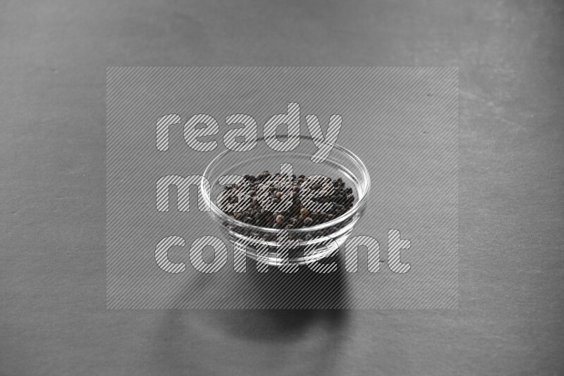 فلفل أسود في وعاء زجاجي علي خلفية سوداء