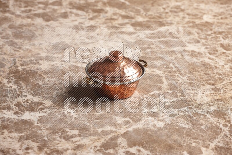 A small copper pot on beige marble background