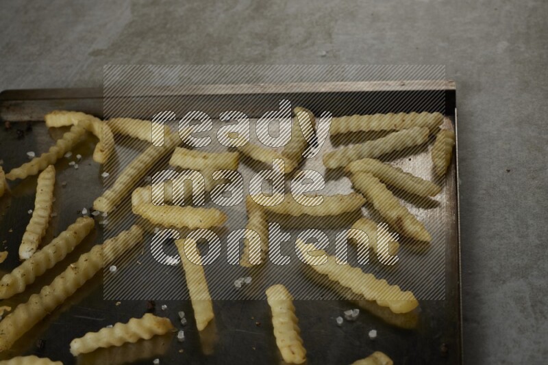 crinkle fries in a black stainless steel rectangle tray on grey textured counter top