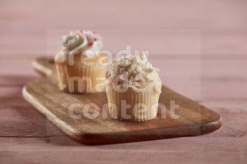 Vanilla mini cupcake topped with coconut on a wooden board