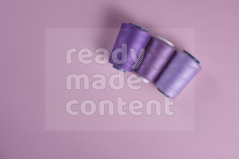 مجموعة من أدوات الخياطة والتفصيل أرجوانية وزهرية اللون على خلفية زهرية