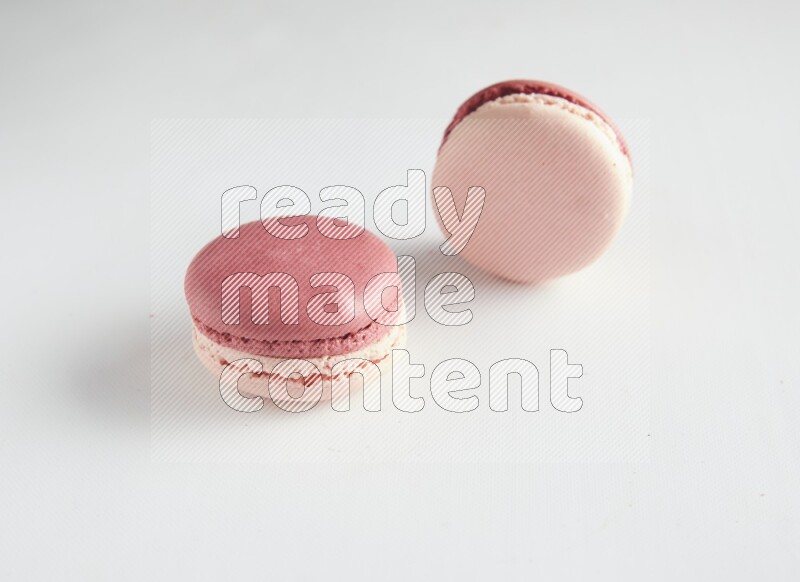 45º Shot of two Pink Litchi Raspberry macarons on white background