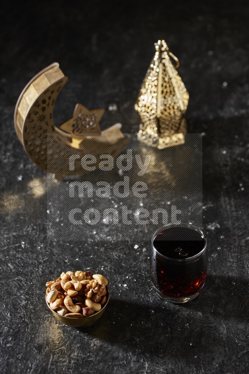 Nuts in a metal bowl with tamarind beside golden lanterns in a dark setup
