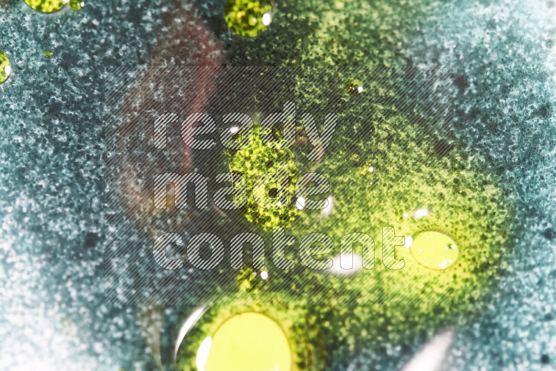 Close-ups of abstract green and yellow watercolor drops on oil Surface on white background