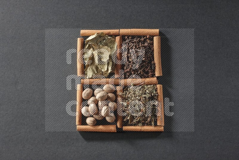 4 squares of cinnamon sticks full of bay laurel leaves, dried basil, cloves and nutmegs on black flooring
