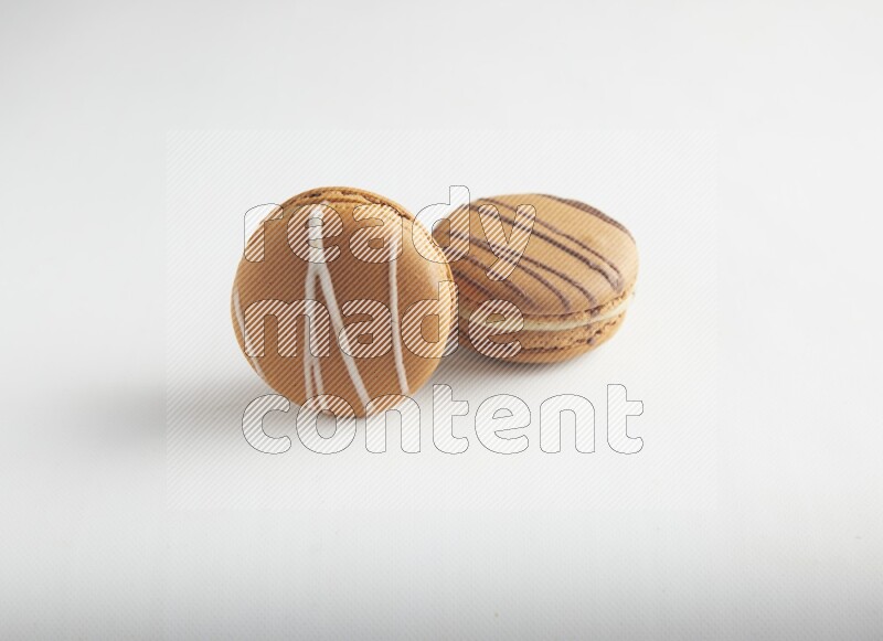 45º Shot of of two assorted Brown Irish Cream, and light brown  Almond Cream macarons on white background