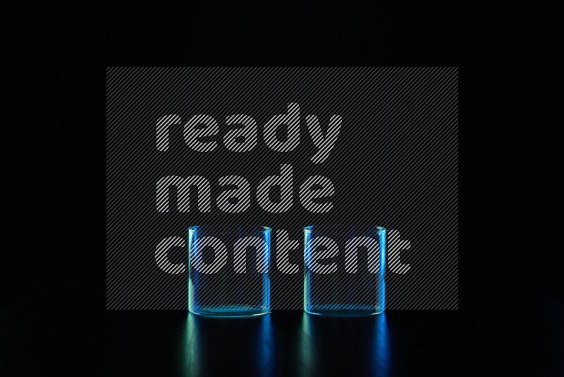 Glassware with rim light in blue and green against black background