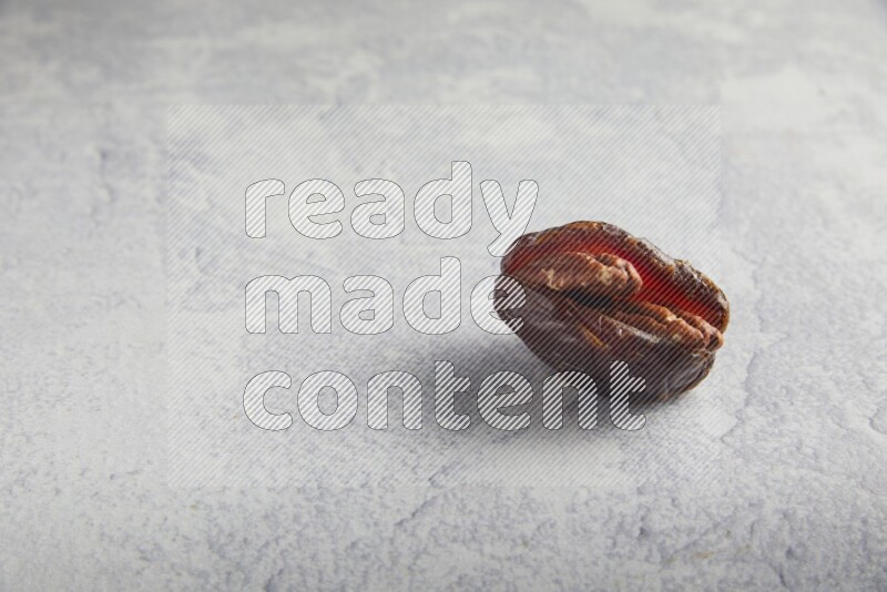 pecan stuffed madjoul date on a light grey background