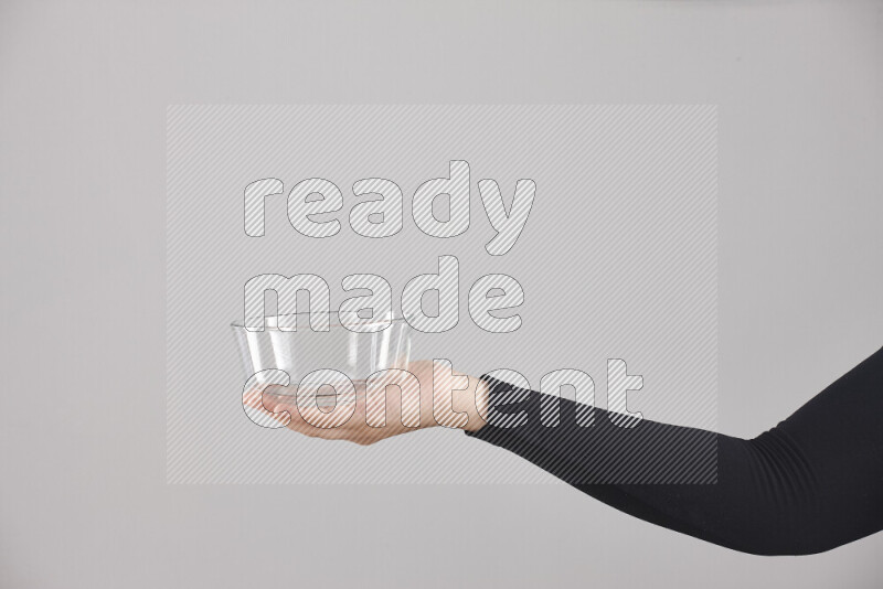 A woman in black abaya holding different glassware in different positions