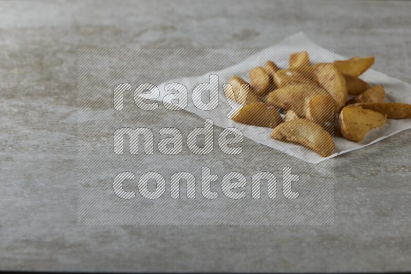 wedges potato on parchment paper on grey textured counter top