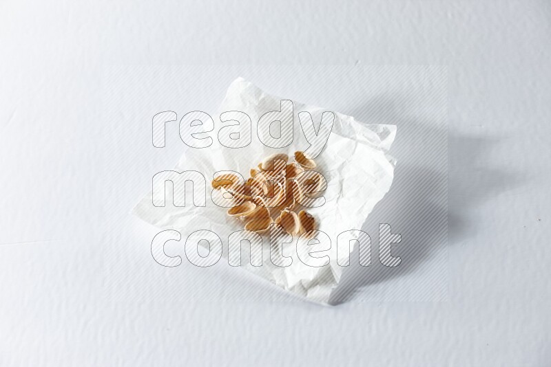 Pistachio peels on a crumpled piece of paper on a white background in different angles