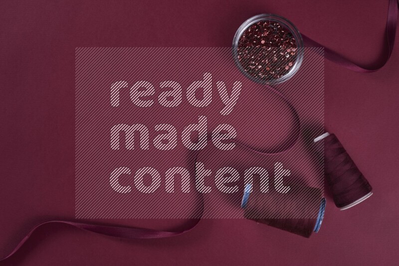 A red collection of sewing and tailoring tools arranged on a red background